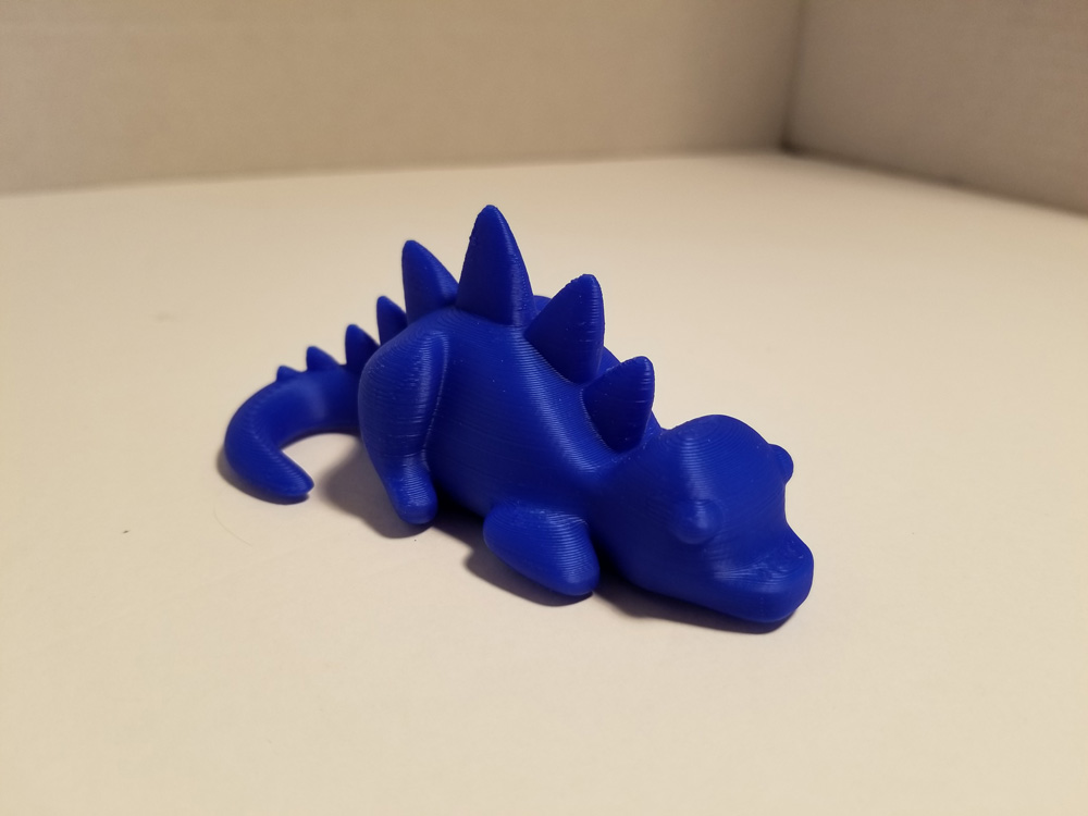 Photo of 3D printout of blue stegosaurus. - front view.